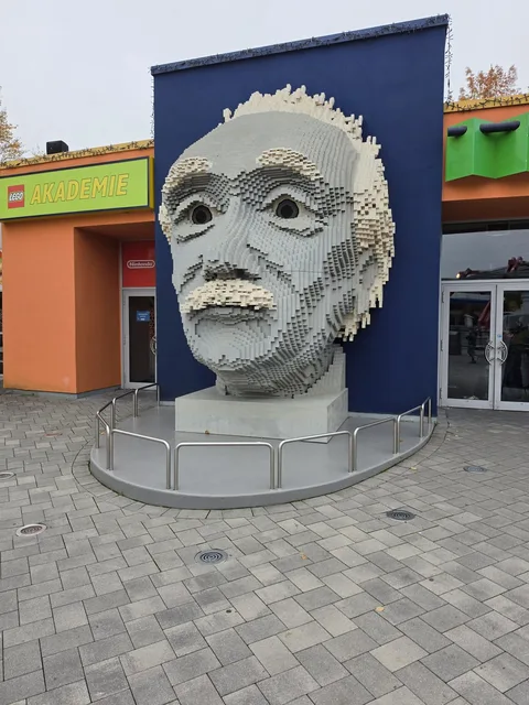 Ein riesiger Kopf von Albert Einstein aus grauen und weißen Steinen auf einem Sockel vor dem Gebäude der LEGO Akademie