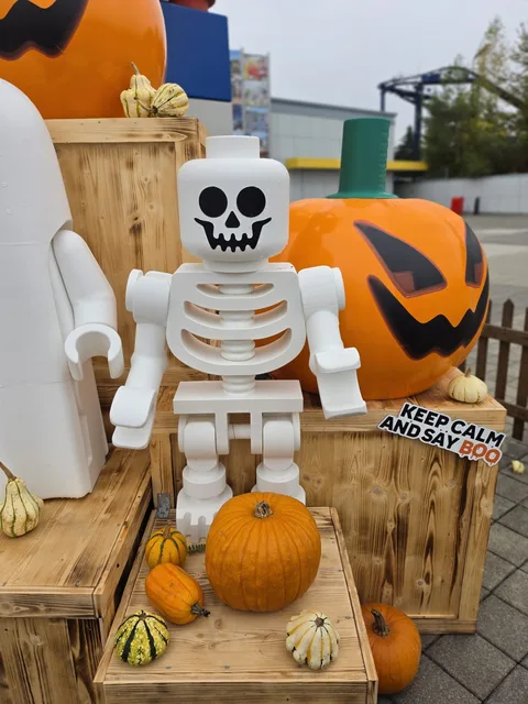 Ein riesiges Skelett als Minifigur aus Steinen mit einem kleinen Kürbis in der Hand, daneben ein Schild „Keep calm and say BOO“