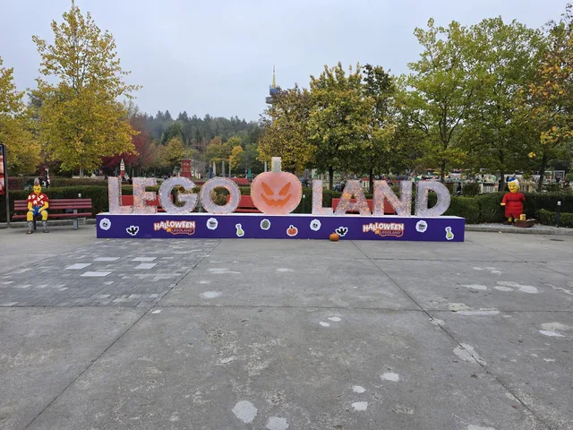 Der LEGOLAND-Schriftzug auf dem Platz im Park, zwischen LEGO und LAND ein geschnitzter Kürbis, davor Halloween-Banner