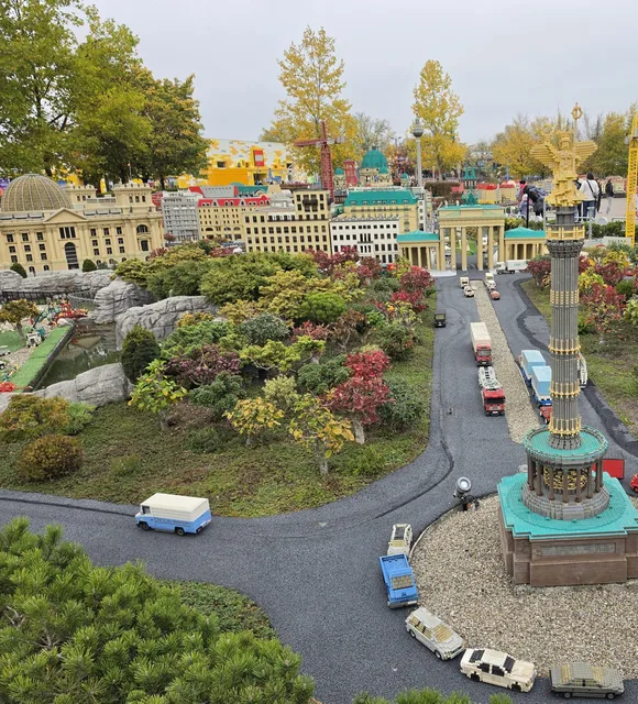 Berlin im Miniland: die goldene Siegessäule im Kreisverkehr mit Autos aus Steinen, eine Straße zum Brandenburger Tor und zum Reichstag, überall Herbststräucher