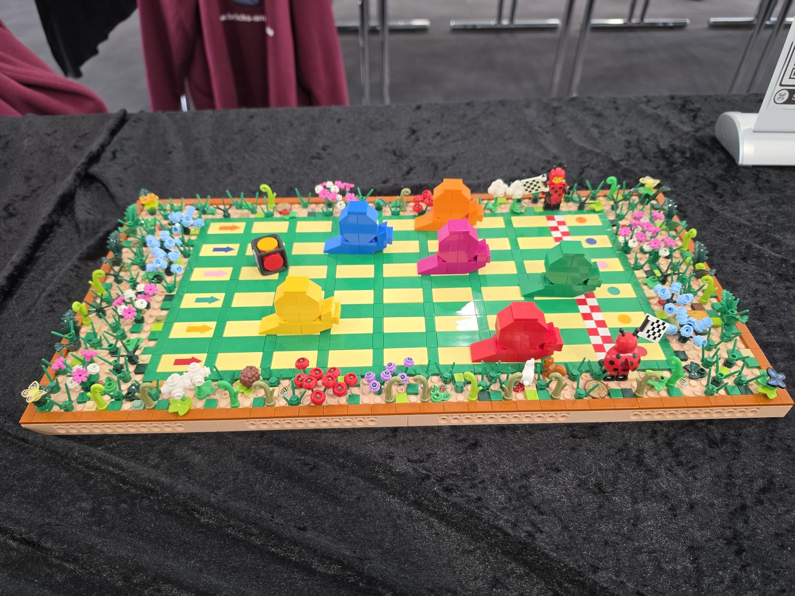 Ein Mensch-ärgere-dich-nicht-Spielbrett, komplett aus LEGO-Steinen gebaut, mit Blumenrand